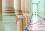 A person walking alone down a column-lined corridor or portico.